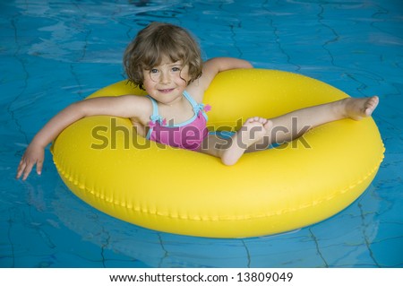 Little girl with inner tube floating on swimming pool