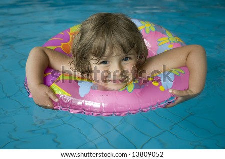 Little girl with inner tube floating on swimming pool