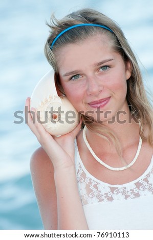 Summer on the beach - beautiful girl with shell in beach resort