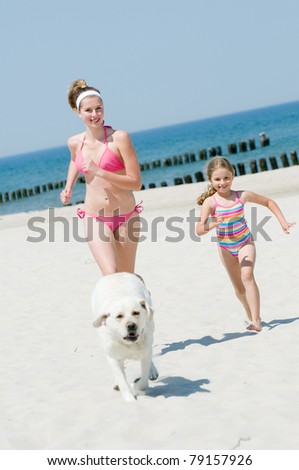 Summer vacation - girls with dog playing on the beach