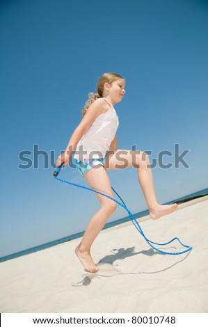 Happy summer  - little girl with skipping rope on the beach