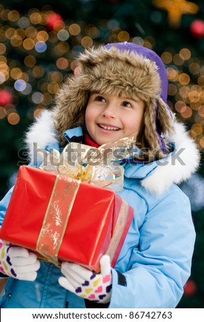 Merry Christmas - Little girl with Christmas gift - Defocused Christmas Tree Lights