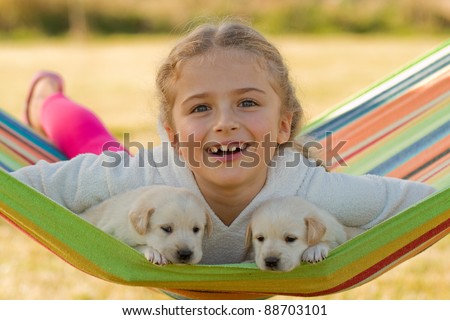 Happy childhood - little girl with cute puppies in hammock