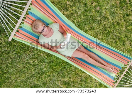 Relax in the garden, woman reading a book in colorful hammock