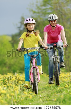 Bike riding - young girl with mother on bike, active family concept