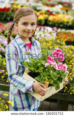 Planting, garden flowers - Lovely girl holding flowers in garden center