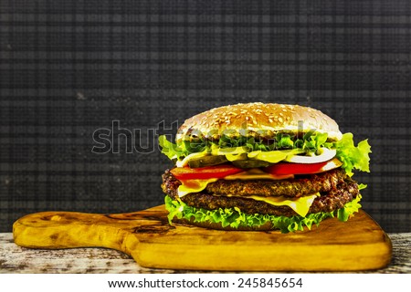 Delicious cheeseburger stacked high with a juicy beef patty, cheese, fresh lettuce, onion and tomato - space for text