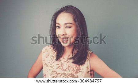 Okay eyes blink. Vintage, retro style of portrait of Asian woman in pink vintage dress on blue - green background.