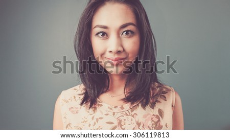 Close up straight face. Vintage, retro style of portrait of Asian woman in pink vintage dress on blue - green background.