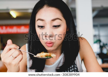 Asian woman is eating rice cooked in chicken broth or Khao Man Kai.