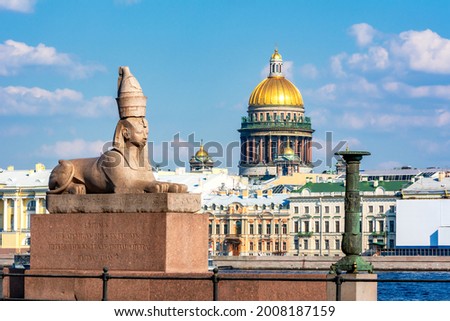 Sphinx statue on University embankment and St. Isaac's cathedral dome, Saint Petersburg, Russia (inscription "Sphinx from ancient Thebes of Egypt transported to city of Saint Peter in 1832")