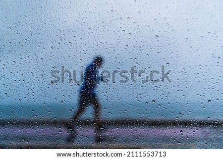 Salvador, Bahia, Brazil - November 15, 2021: A person walking along the waterfront in the middle of the rain. Salvador, Bahia, Brazil.