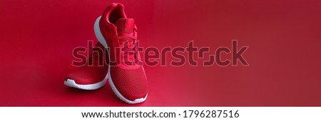 Close-up of red sneakers on bright backdrop. Sport footwear for running and fitness. Amazing pair of shoes. Active lifestyle. Nice texture with white sole and laces Foto d'archivio © 