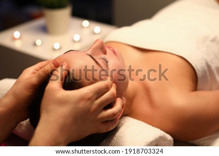 Woman is given rejuvenating facial massage in an aroma room. Relaxing facial massage techniques concept