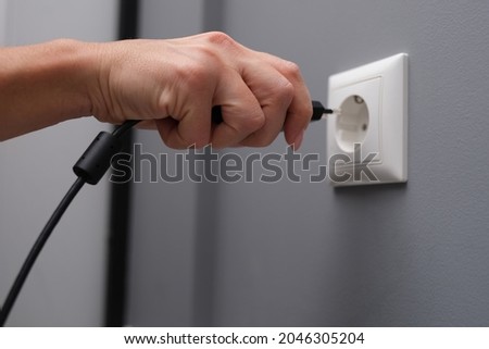 Woman hand inserts electrical plug into outlet closeup 商業照片 © 