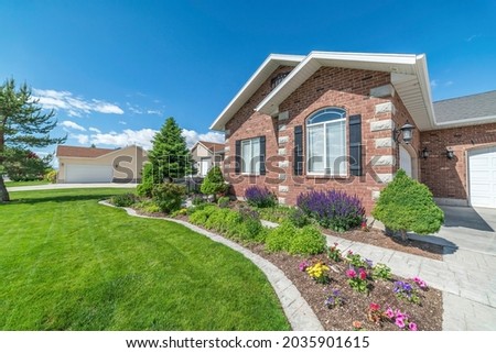 Facade of a house with colorful front yard garden and concrete walkway Foto stock © 