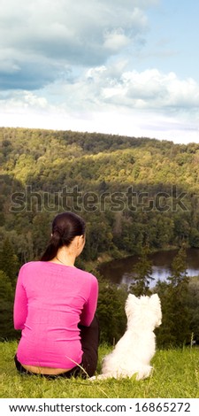 Young woman sitting on the hill with white dog