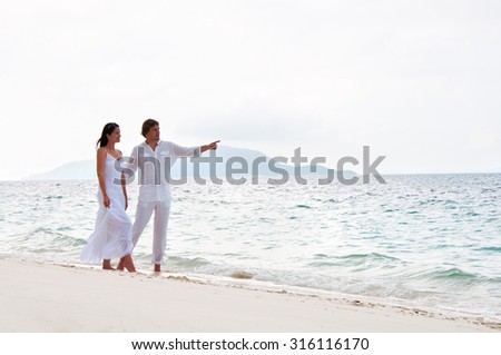 Picture of romantic young couple having a walking on the sea shore