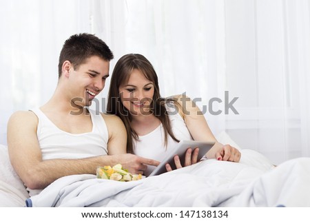 Happy young couple surfing the internet on a digital tablet PC