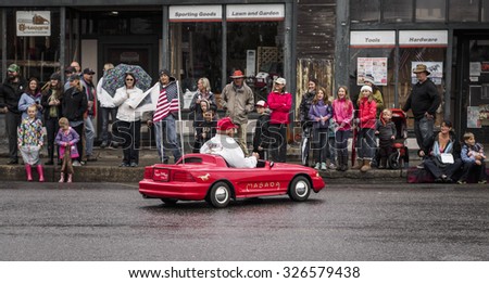 ROSLYN, WA - September 6, 2015: Labor day weekend parade attendees greet a member of the Shriners in his signature mini red car.