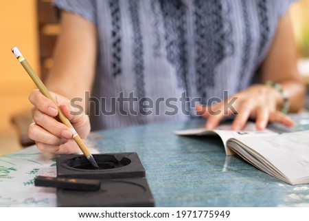 close up hands of senior woman practices eriting calligraphy of traditional chinese characters (focus at tip of brush) Stok fotoğraf © 