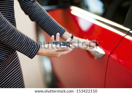 Beautiful young girl with car key in hand and opens the car