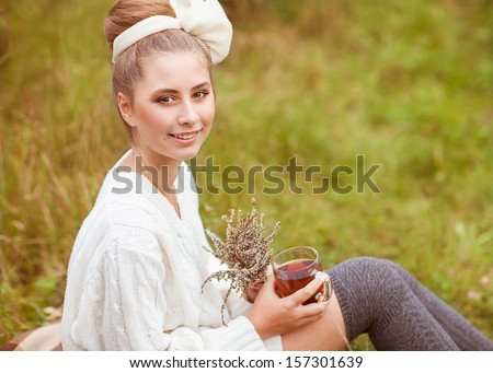 Pretty young girl drinks tea in retro clothes, enjoying autumn day
