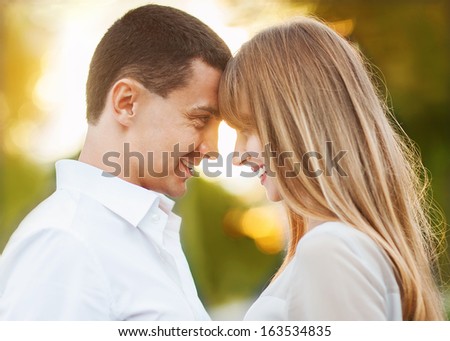 Young couple in love outdoor. They are smiling and looking at each other.