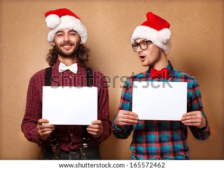 Christmas, x-mas, people, advertisement, sale concept - happy two man in santa helper hat with blank white board. Hipster style.