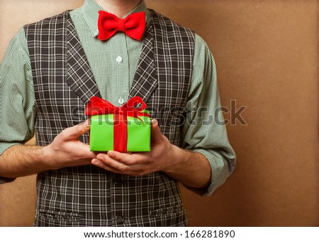 guy holding a gift in a suit and bow tie in a cage