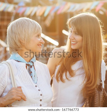 Adult mother and daughter after shopping walk down the street and talk.
