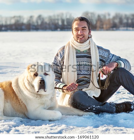 Man and central Asian shepherd playing with his dog outdoors