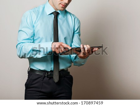 Serious young male executive using digital tablet against gray background