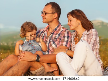 Happy mother, father and daughter in sunset