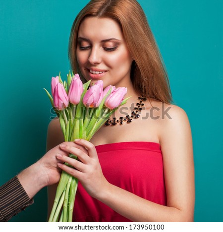 Young beautiful girl gives a bouquet of tulips man, holding out his hand with a bouquet. Celebrating valentine