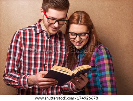 young couple in clothes and stylish hipster glasses reading a book. studio shot