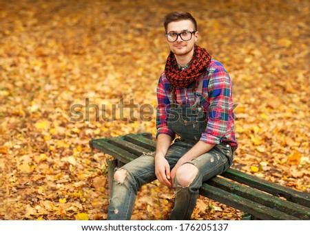 Young hipster relaxed man in nature, back on tree, meadow behind