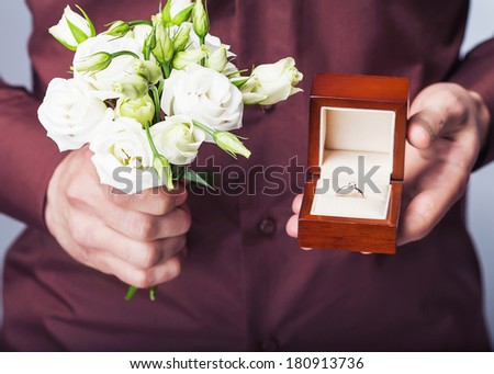 Man holding ring box and a bouquet of flowers
