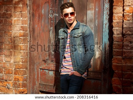 Hipster style guy. Fashion man standing near a wooden door