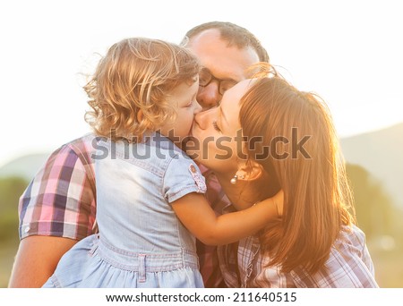 Dad Mom and daughter kissing