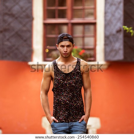 Hipster style guy. Fashion man standing near wall street orange