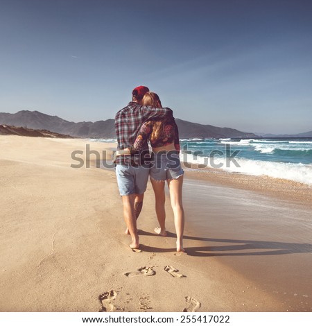 couple in love walk on the sea playing happily at sunset