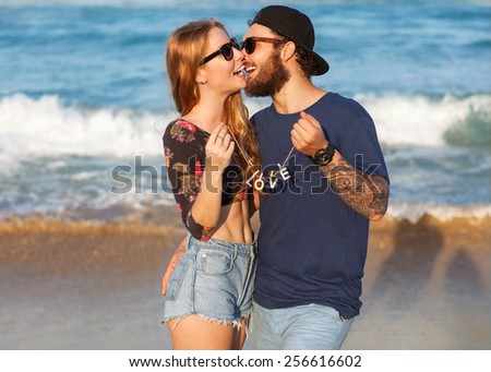 Young couple in love walking in the sea holding hands looking in the sunset, concept of Valentine\'s Day