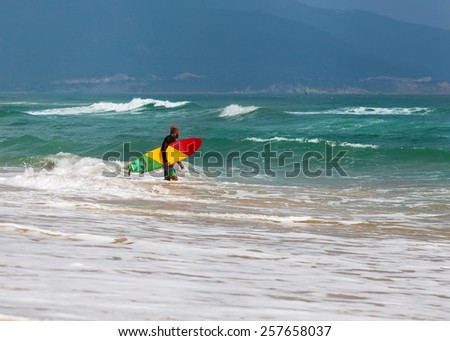 Surfer at the sea is standing with a surf board bright color.