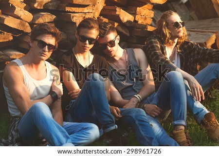 fashion guys friends sitting on the grass, wood backgrounds, sunset
