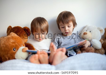 Two boys, reading a book, educating themselves