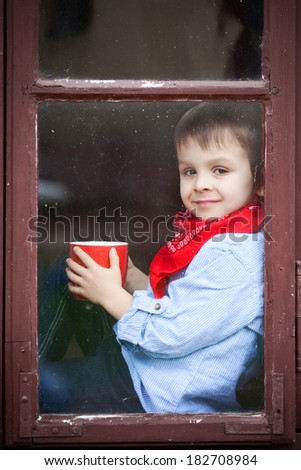 Boy on the window, smiling and drinking tea, having fun