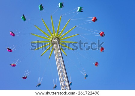 Merry-go-round, chain swing carousel ride in amusement park, shot from below, blue sky