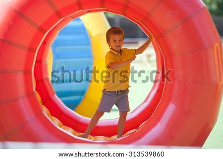 Cute little boy, playing in a rolling plastic cylinder ring, full with air, outdoor