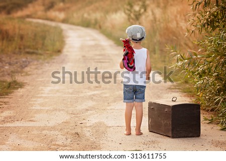 Cute little boys, holding a bundle, eating bread, walking bare feet on a dusty rural road